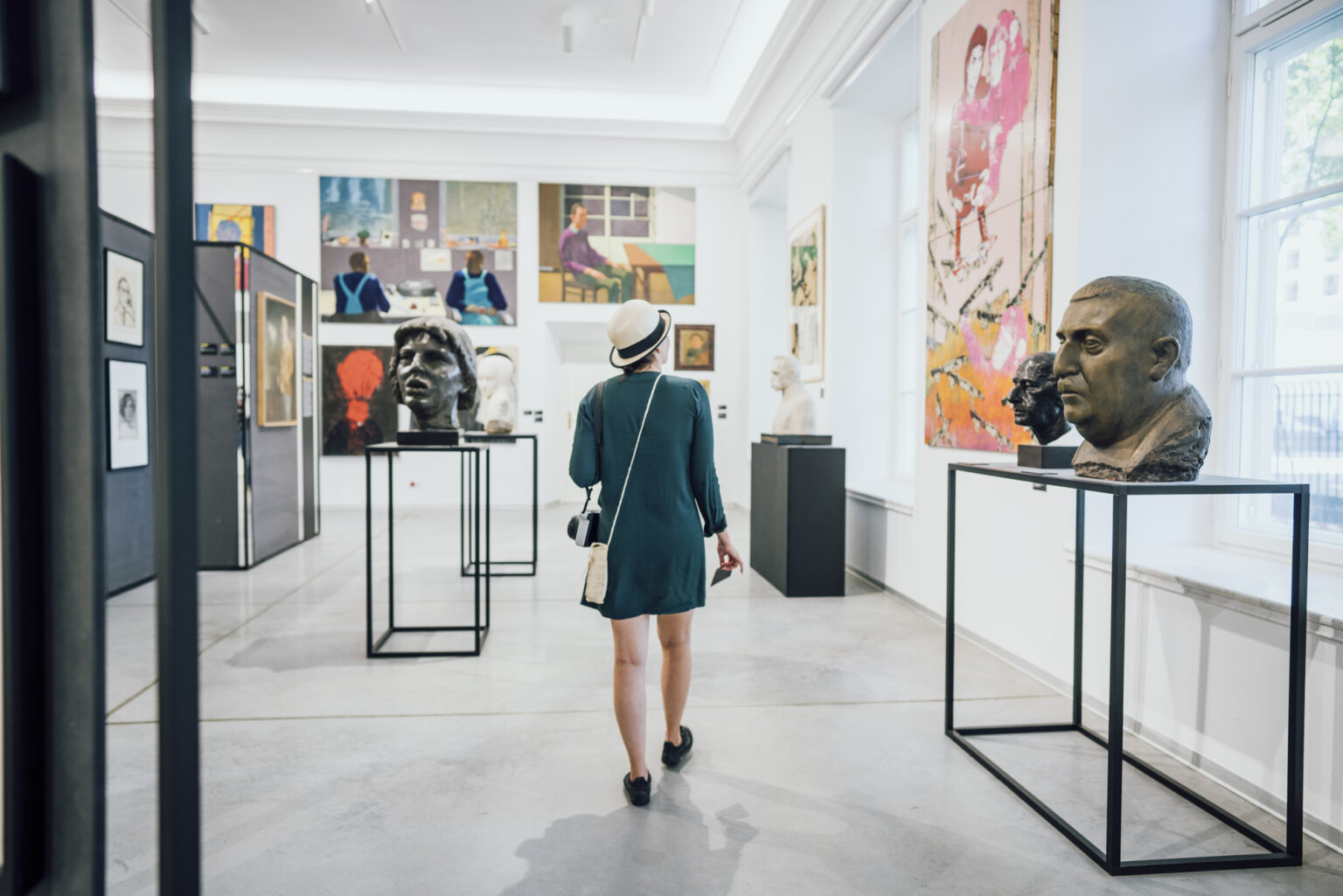 A female figure wearing a hat in the exhibition space.